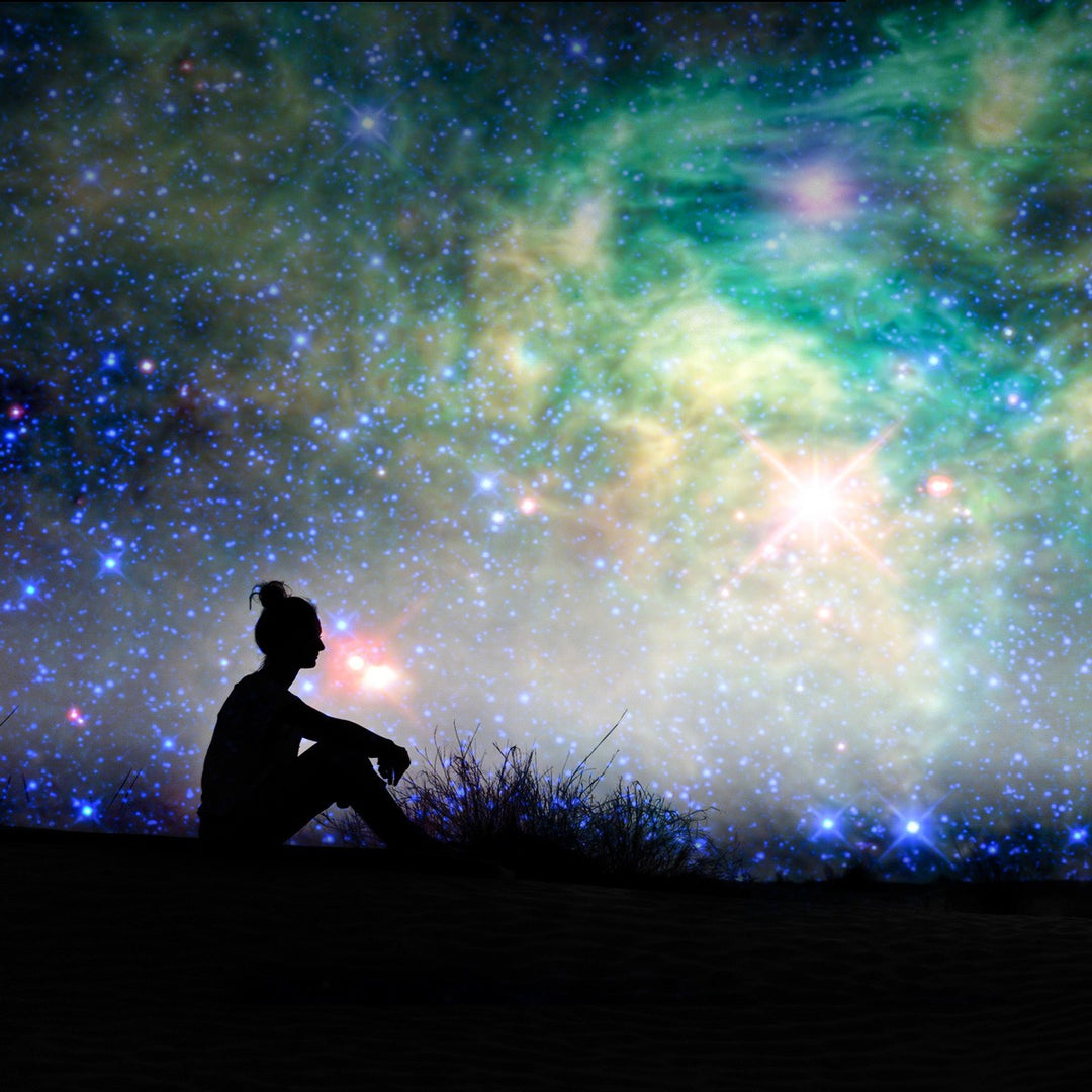 girl sitting in silhouette with a starry sky above her