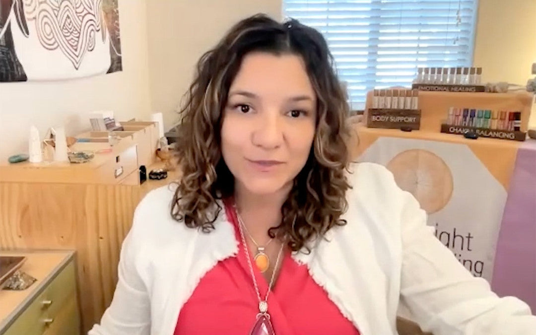 Healer with curly hair, wearing red top and white cardigan, in spiritual healing space with energy tools