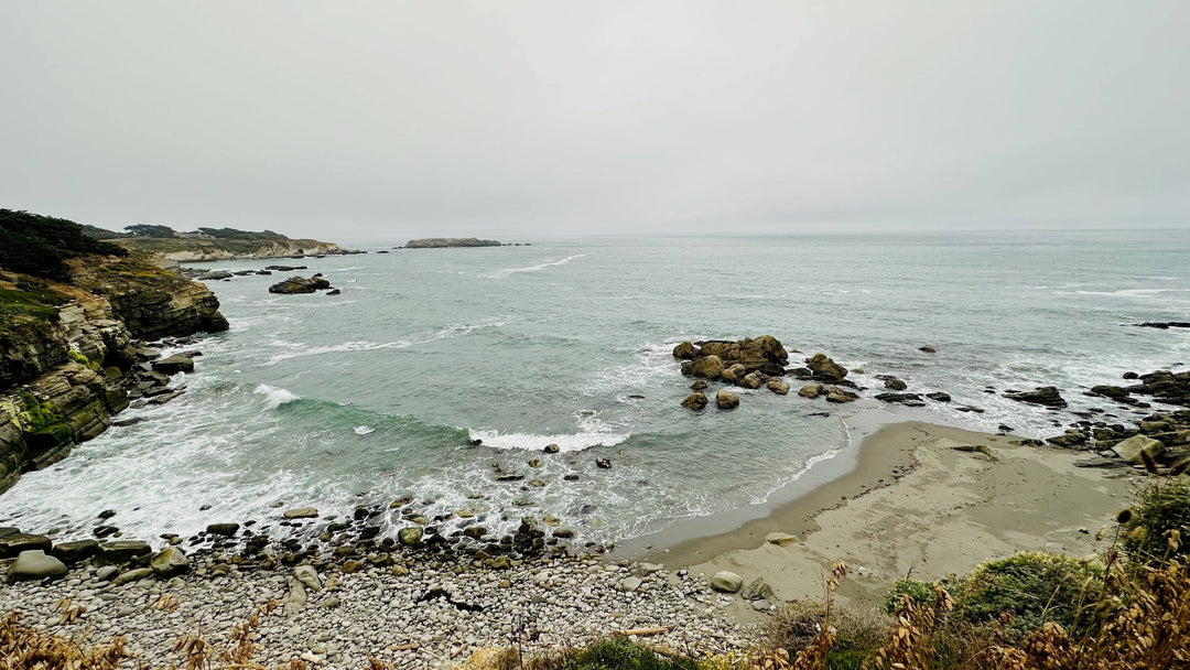 Serene coastal scene with misty ocean, rocky cliffs, and pebble beach — perfect for spiritual healing and ascension journeys.