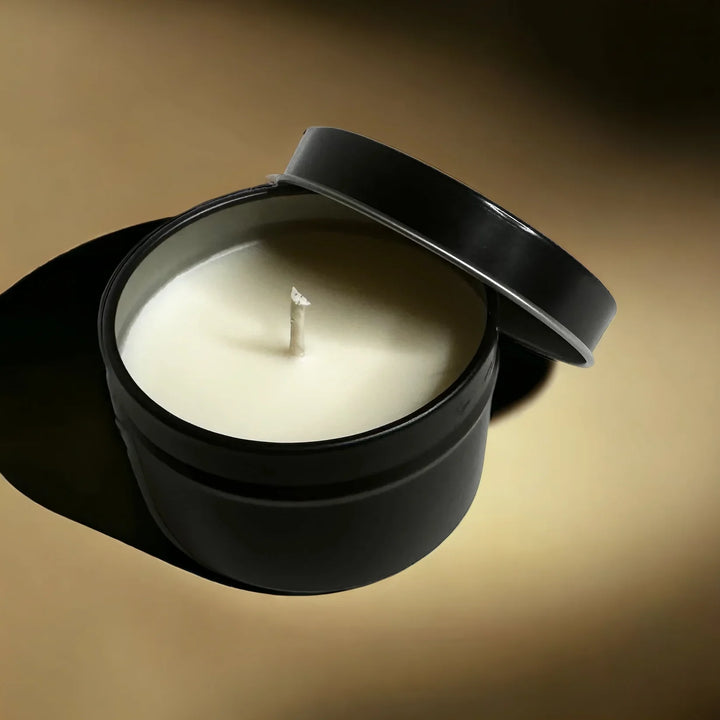 Black candle holder with a white candle on a brown background