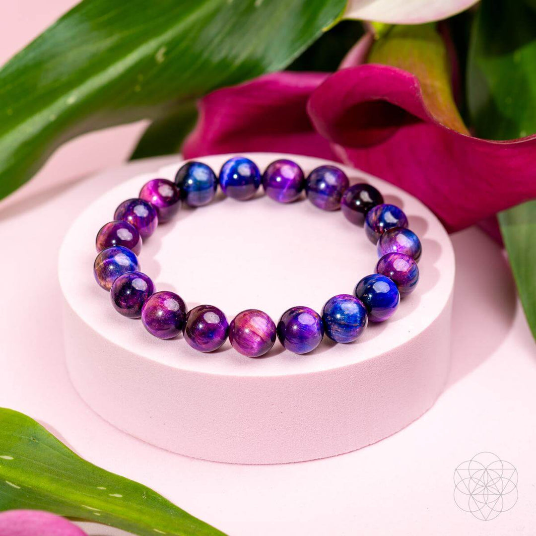 Multicolored beaded bracelet on a pink stand with pink flowers and green leaves in the background