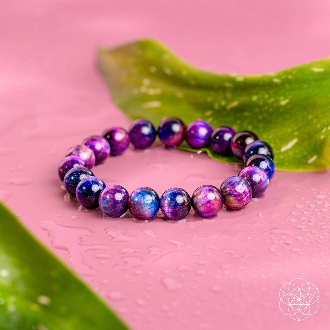 Multicolored beaded bracelet on a pink surface with green leaves