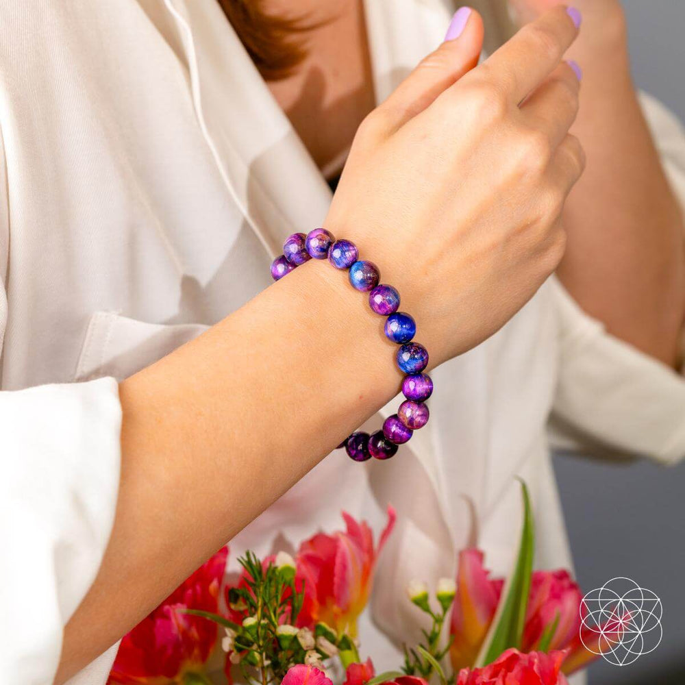 Person wearing a colorful beaded bracelet with flowers in the background