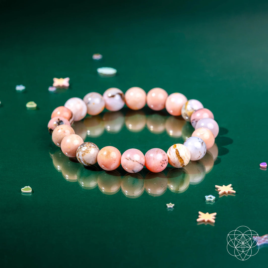 Beaded bracelet on a reflective green surface with decorative elements