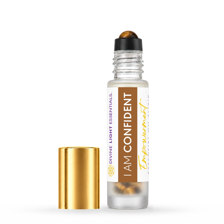 I Am Confident roller bottle with its crystal rollerball exposed and gold cap beside it on white.