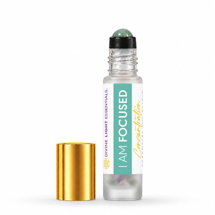 A clear glass roller bottle labeled I AM FOCUSED by Divine Light Essentials, shown with its detached shiny gold cap on a clean white background.