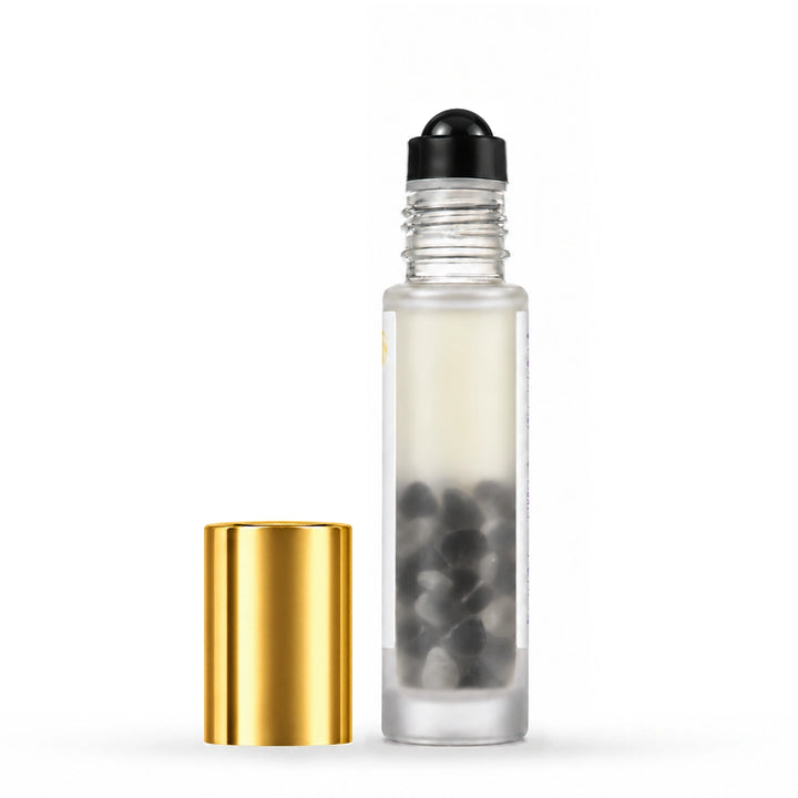 A clear glass roller bottle with a black spherical cap and a separate shiny gold cap, shown on a clean white background.
