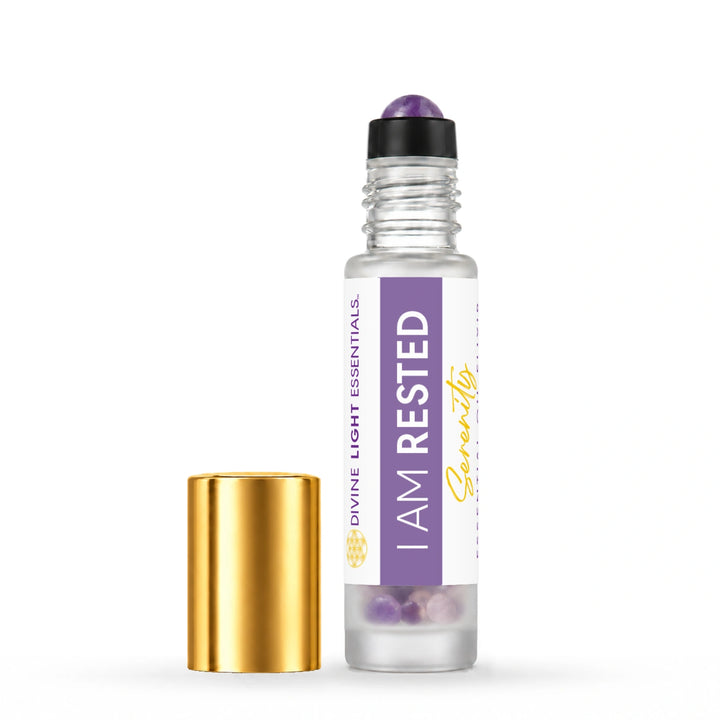 I Am Rested roller bottle with its crystal rollerball exposed and gold cap beside it on white.