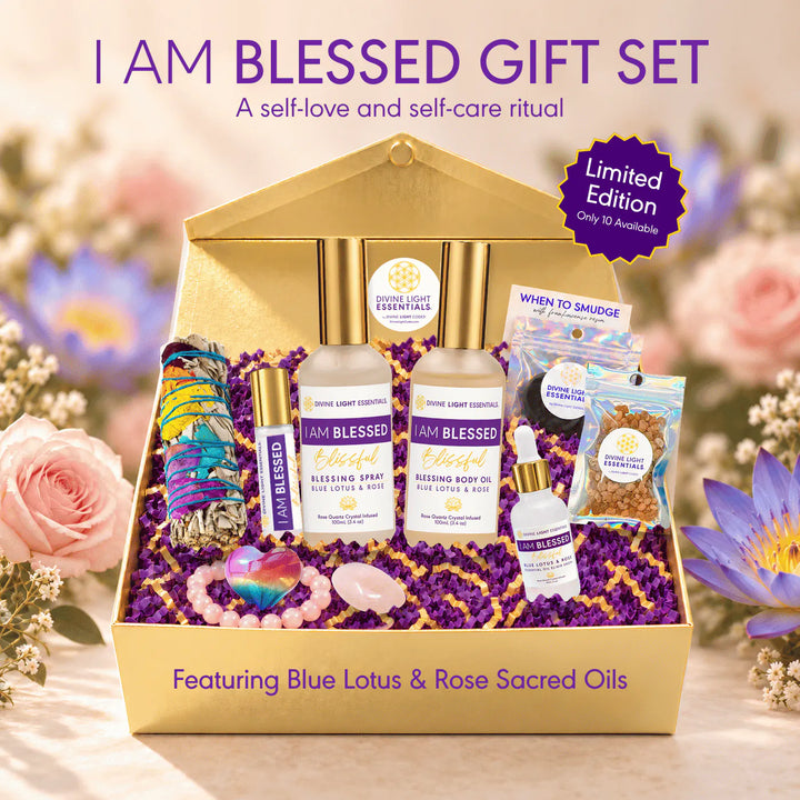 A gold gift box filled with self-care and spiritual items, including two bottles of I Am Blessed essential oils, a colorful bracelet, crystals, and small sachets, set against a soft floral background with promotional text.