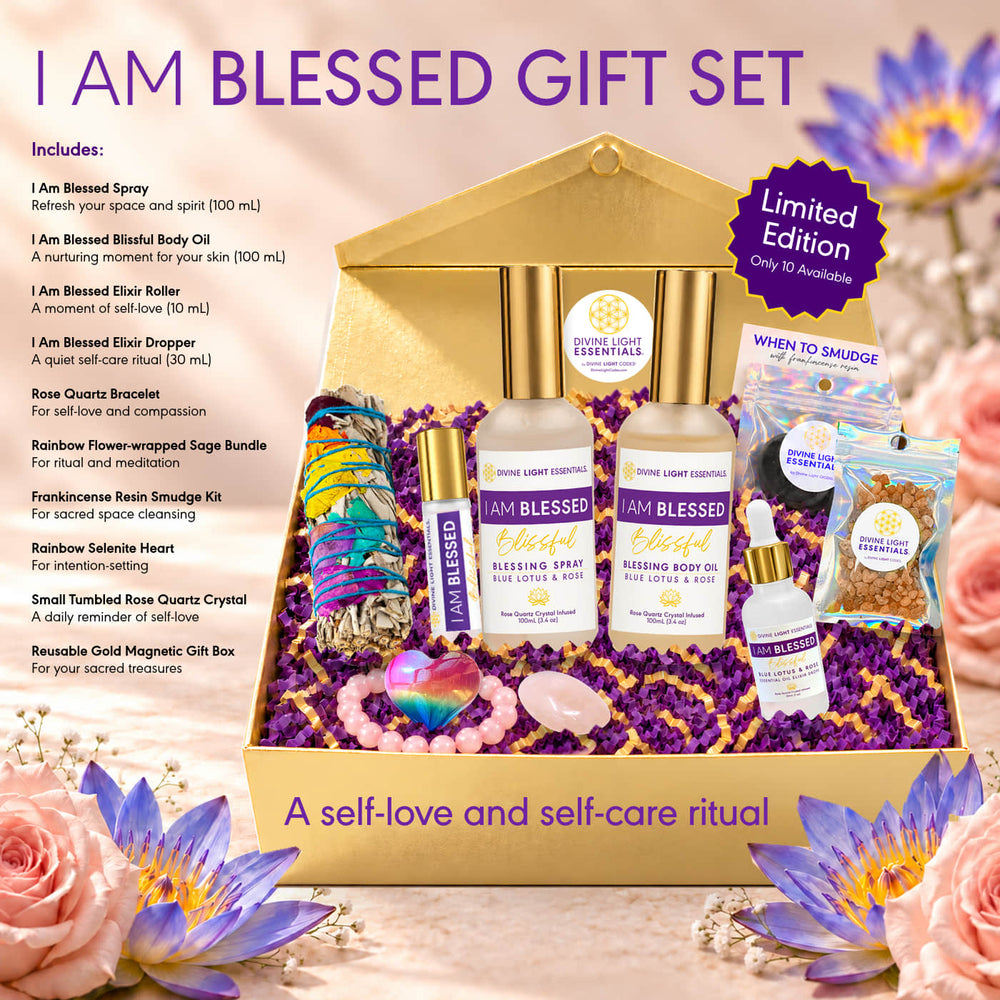 A self-care and spiritual gift set displayed in a gold box with purple crystals, surrounded by flowers and a printed inclusion list. The set includes Blessed Body Oil, Blessed Elixir Roller, Blessed Elixir Dropper, Sacred Light Essentials spray, a Rainbow Flower-wrapped Sage Bundle, a Rainbow Smudge Kit, a When It Rains Smudge, a Rainbow Rose Quartz Crystal, and a Healed Gold Magnetic Gift Box.