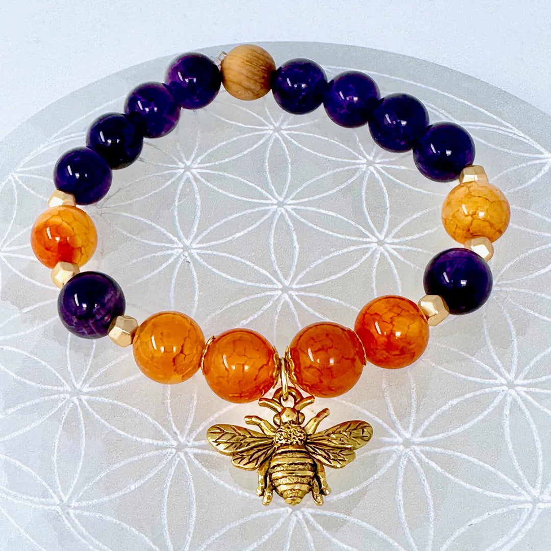Amethyst and carnelian beaded bracelet with gold bee charm on sacred geometry background