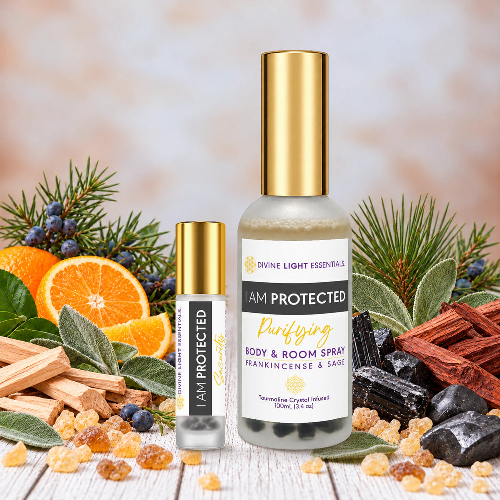 I Am Protected spray and roller duo with gold caps, surrounded by juniper berries, sage, pine, sandalwood, rosewood, wild orange, frankincense resin, black tourmaline and shungite on a pale wood surface.