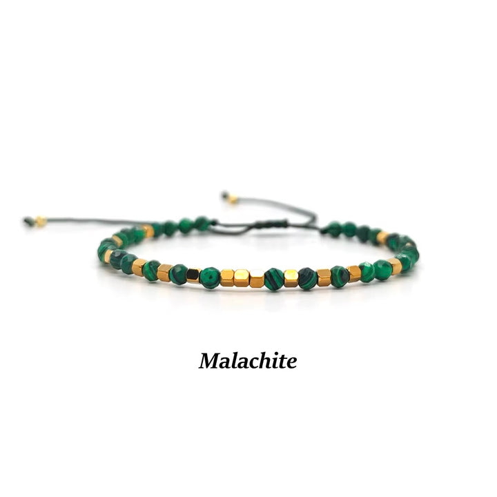A beaded adjustable cord bracelet made of green malachite beads and small gold spacer beads, shown on a white background with the text &