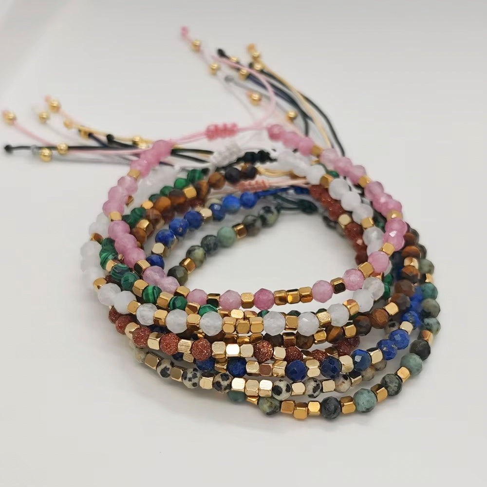A stack of multicolor beaded bracelets with gold-tone metal accents, displayed on a clean white background.