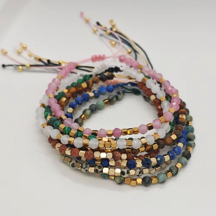 A stack of multicolor beaded bracelets with gold-tone metal accents, displayed on a clean white background.