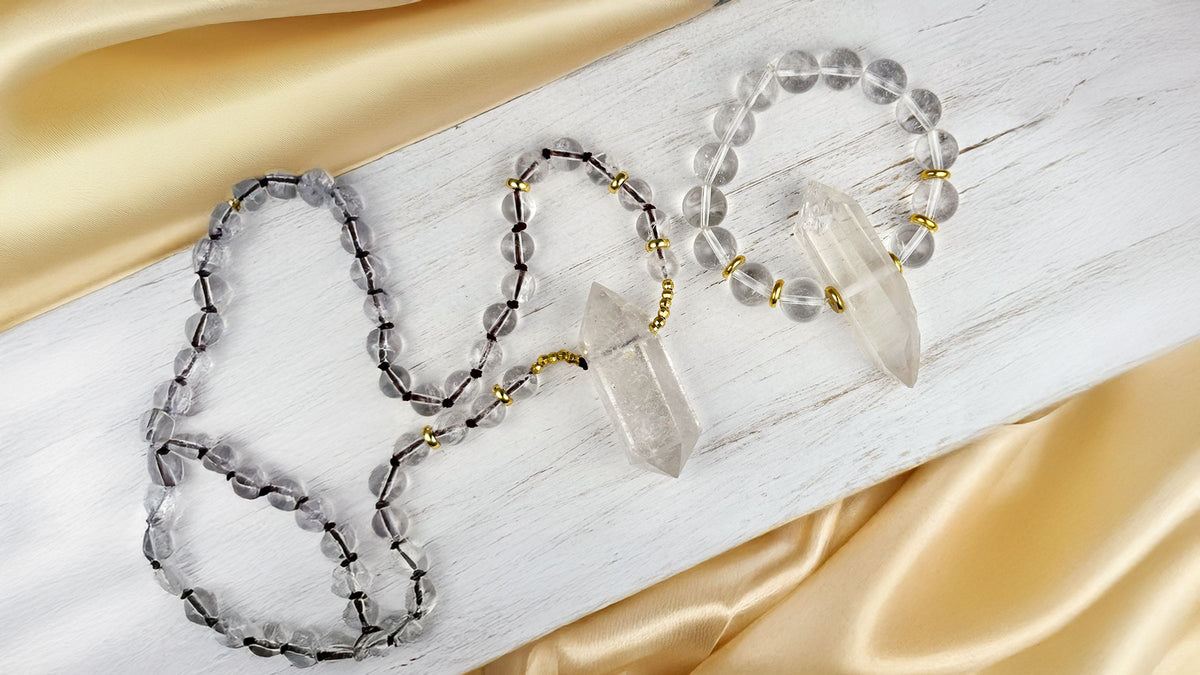 Necklace with clear and black beads on a white and gold fabric background