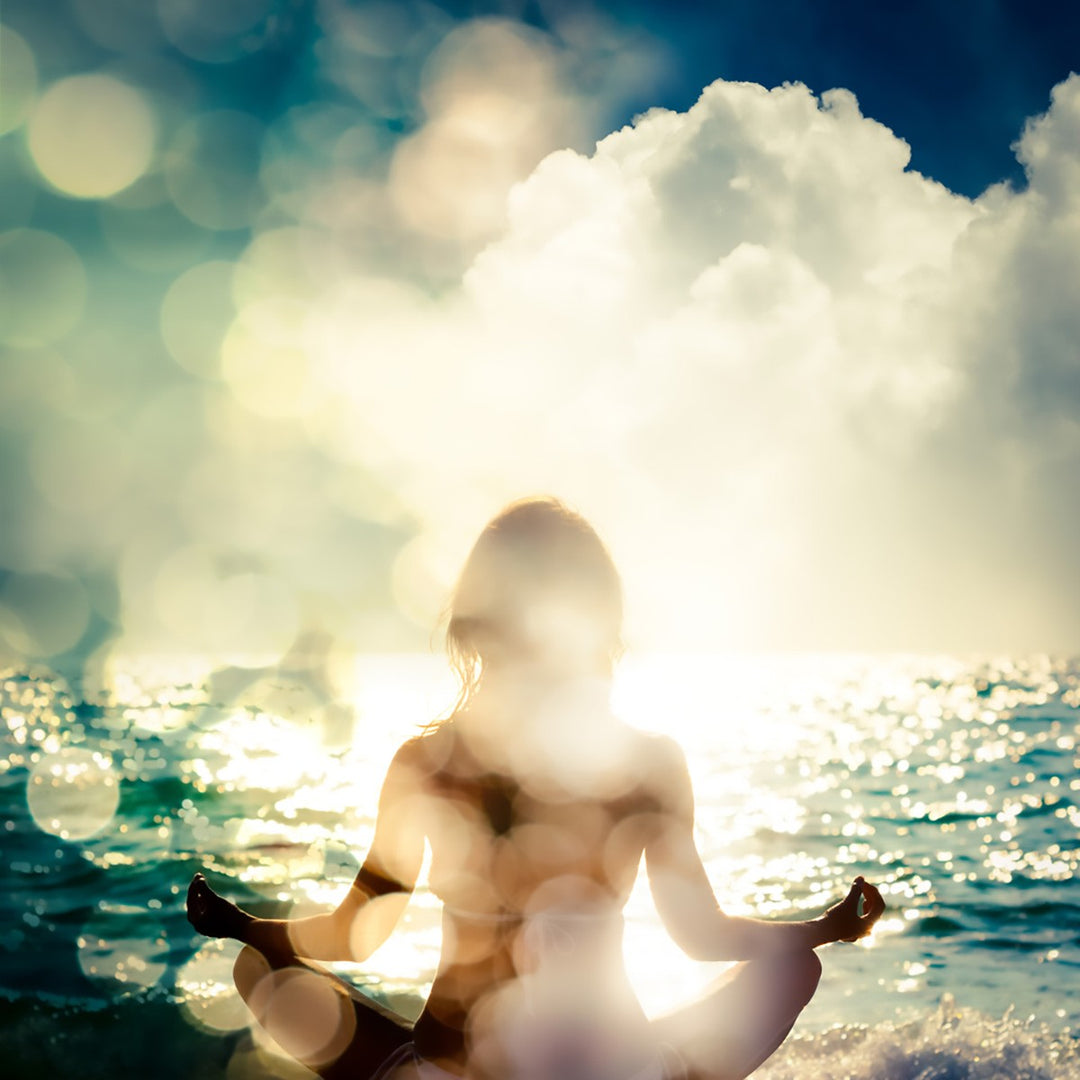 girl sitting with her arms out facing the ocean