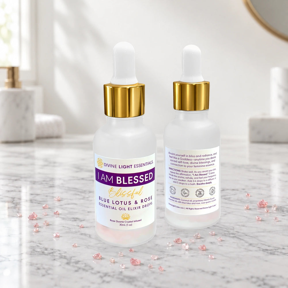 Two frosted glass dropper bottles of Divine Light Essentials Blue Lotus & Rose Essential Oil Elixir shown on a marble surface, with one bottle displaying the front label and the other showing the back packaging.