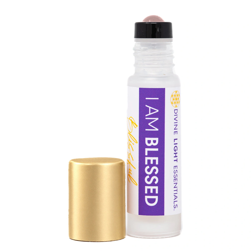 A clear glass roll-on bottle labeled 'I AM BLESSED' by Divine Light Essentials, shown next to its detached metallic gold cap on a plain white background.