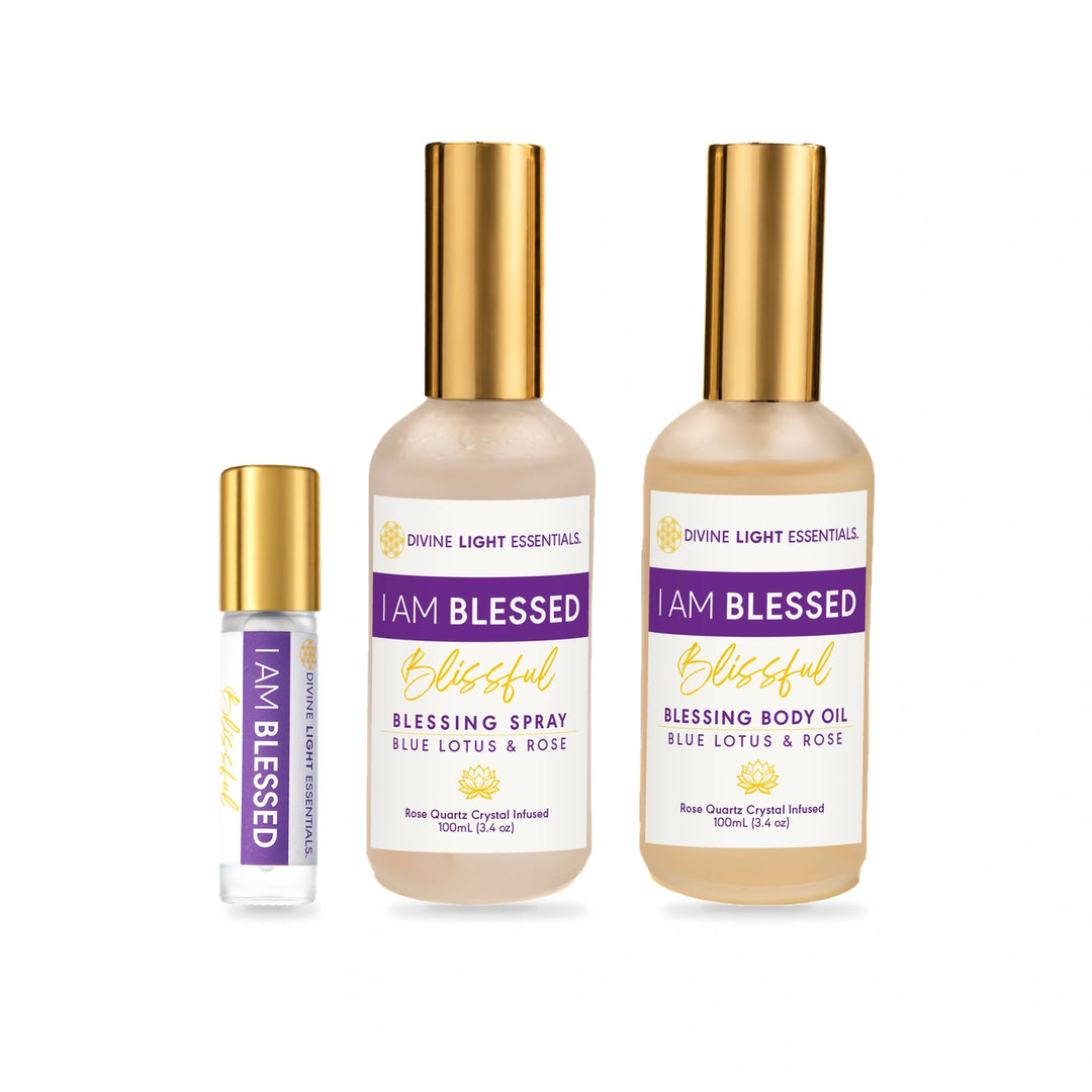Three Divine Light Essentials 'I Am Blessed' fragrance products on a white background: a small roller bottle, a body oil bottle, and a spray bottle, all with gold caps and cream-colored labels with purple and gold text.