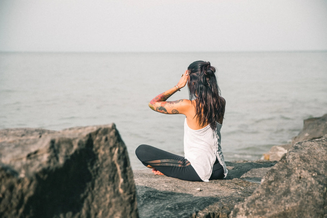 Woman meditating beside the sea on a rocky shoreline