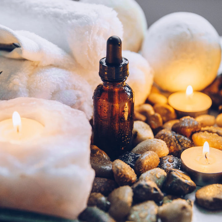 Amber dropper bottle with healing oils, candles, and crystals for spiritual wellness and ascension support