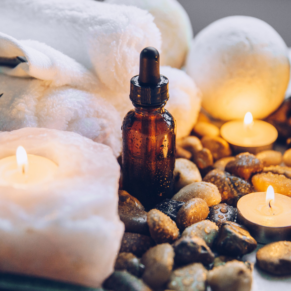 Amber dropper bottle with healing oils, candles, and crystals for spiritual wellness and ascension support
